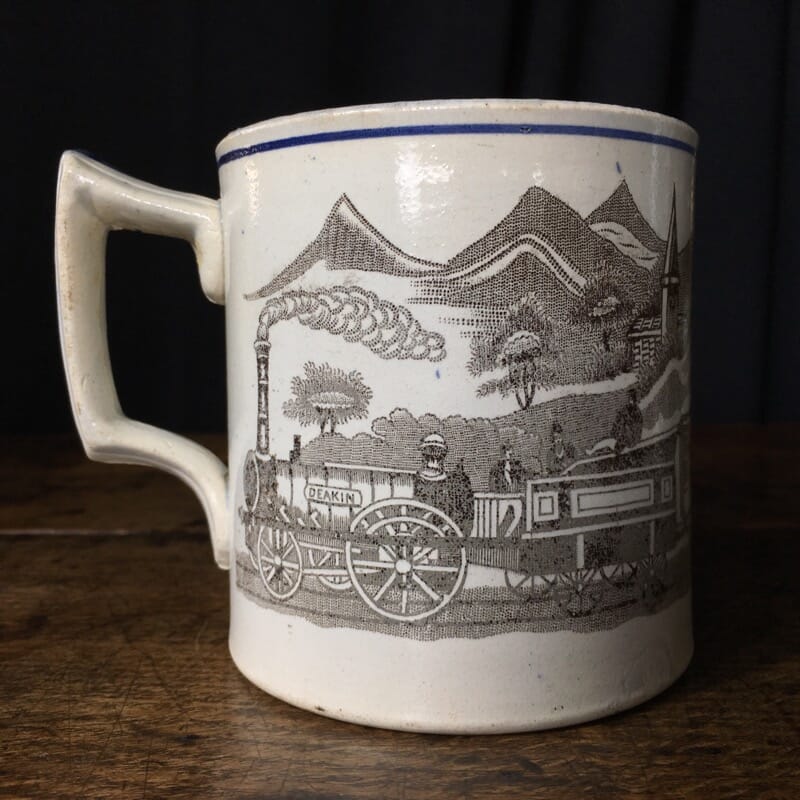 Pottery mug with a train scene, titled DEAKIN, circa 1865 -0