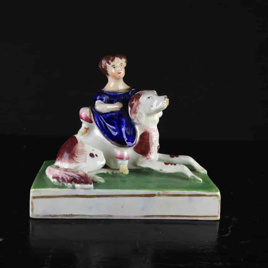 Staffordshire porcelain of a child seated on a dog,  circa 1825-45. -0