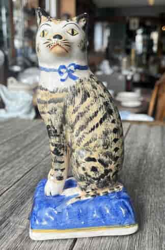 Staffordshire tabby cat seated one blue cushion, Late 19th C