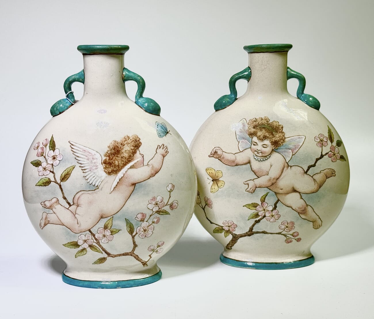 Pair of Minton's Art Studio ‘Moon Flasks’, E.J. Strutt decorated with cherubs, 1873